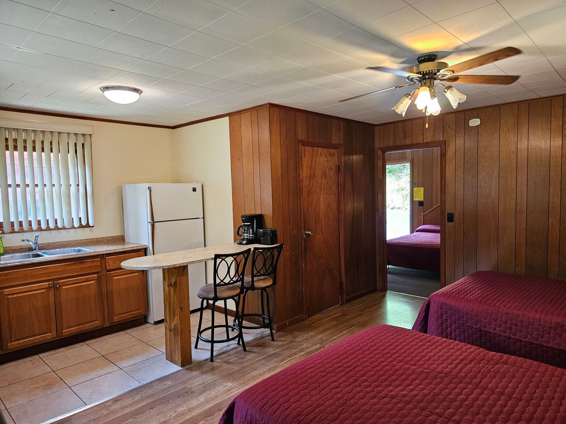 Cozy accommodation featuring two beds, a kitchenette with a refrigerator, and a small dining area, ideal for comfortable stays.
